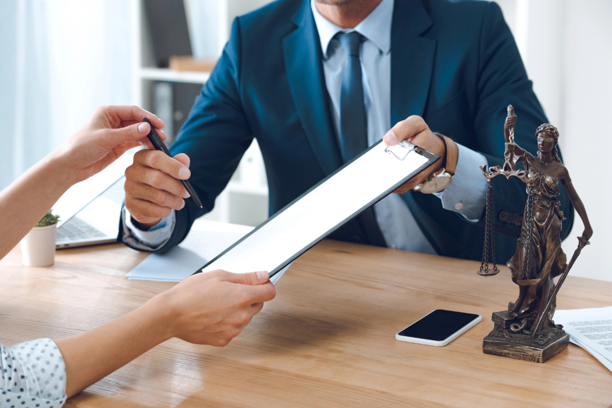 Cropped shot of lawyer giving clipboard and pen to young woman in office Cropped shot of lawyer giving clipboard and pen to young woman in office